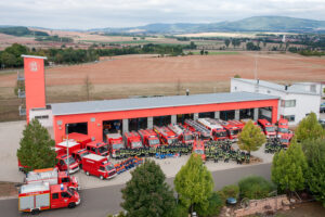 Feuerwehrautos + Feuerwehrleute vor dem Gerätehaus Gölhleim